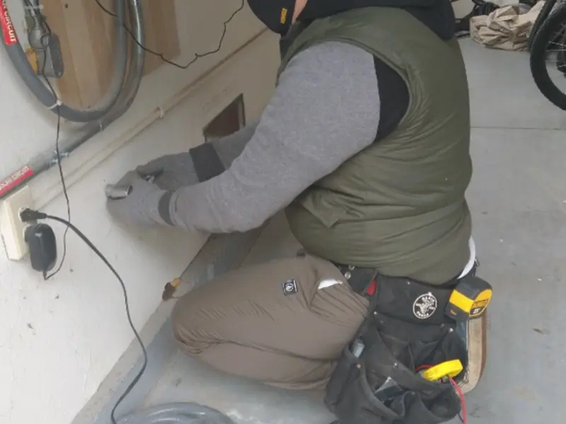 Electrician performing outlet wiring in a Hilton garage